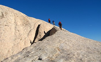 A group of people hike up a rocky face