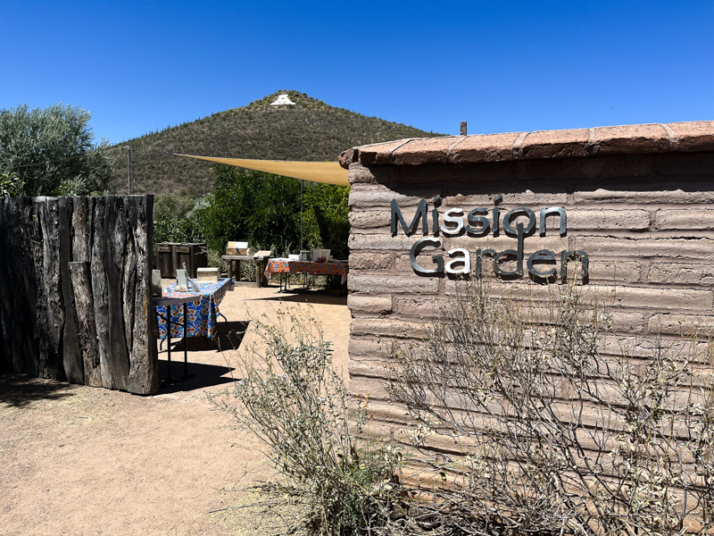 High adobe walls and an orchard mark the entrance to Mission Gardens; Sentinel Peak (