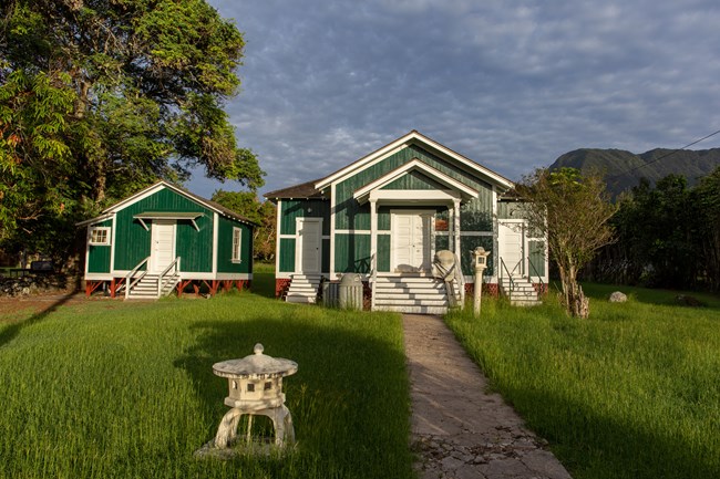 Two teal buildings with white doors and framing and a darker, shingled roof.