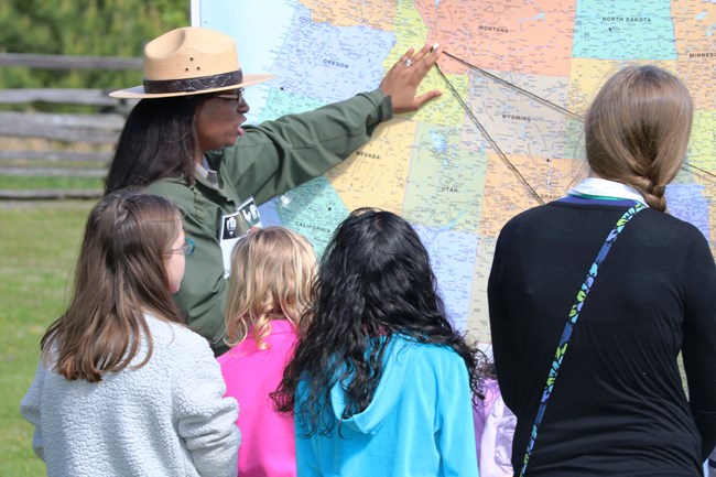 Ranger points at map of United States while speaking with students.