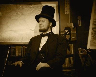 Man dressed as Abraham Lincoln sits in chair