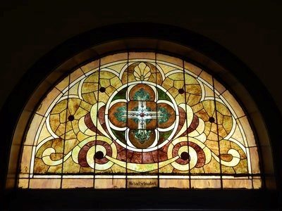 A stained glass window in a church is labeled with the name "Michael Schmalzel."