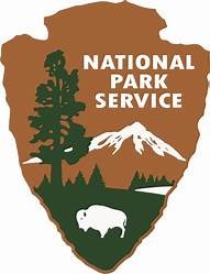 A arrow shaped logo has "National Park Service" typed on it along with a tree, mountains and a bison drawing.