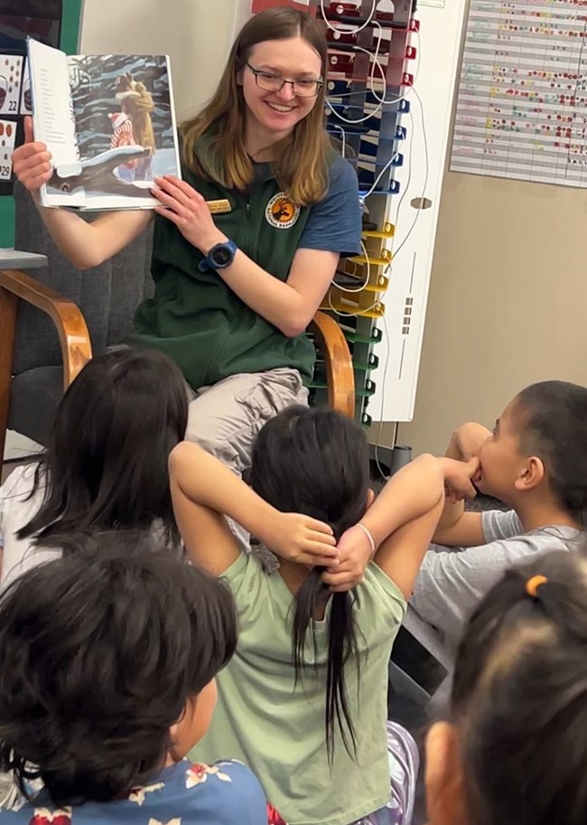 A ranger reads a book to a group of students.