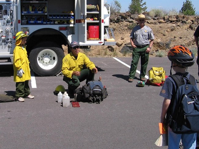 A firefighter talks to kids and a ranger about wildland fire.