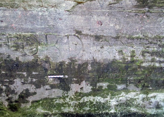 close-up of a rock wall inside the cave, which faintly shows “FORD” carved into the surface.  The ”F” is less obvious than “ORD.”