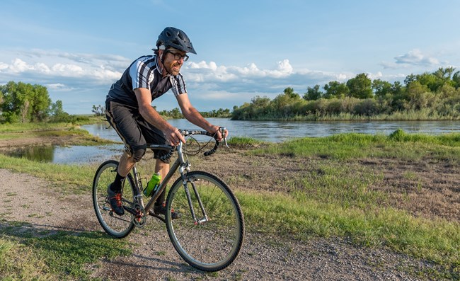 A man bikes on a trail by a river