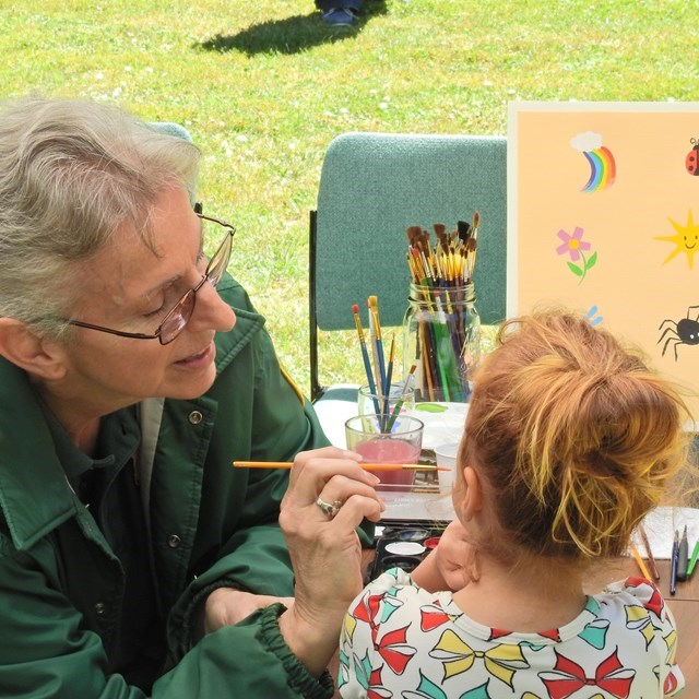 Volunteer paints a child's face