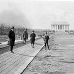 on left, men stand on drained lincoln memorial reflecting pool; memorial looms in right background, B&W