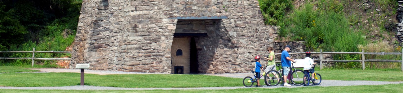 A family on bicycles reads information at a historic site.