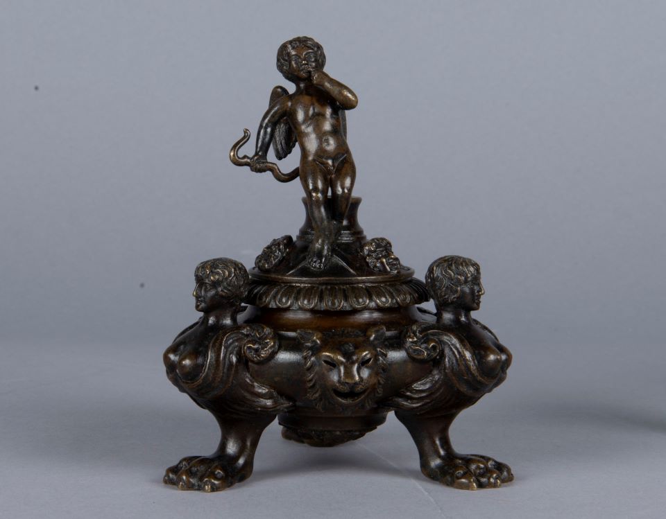 Bronze inkstand with human figures at three corners, lion face on base, and standing cupid holding bow on top