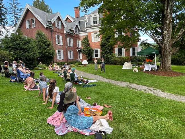 group of people sits on blankets and watches performance outdoors