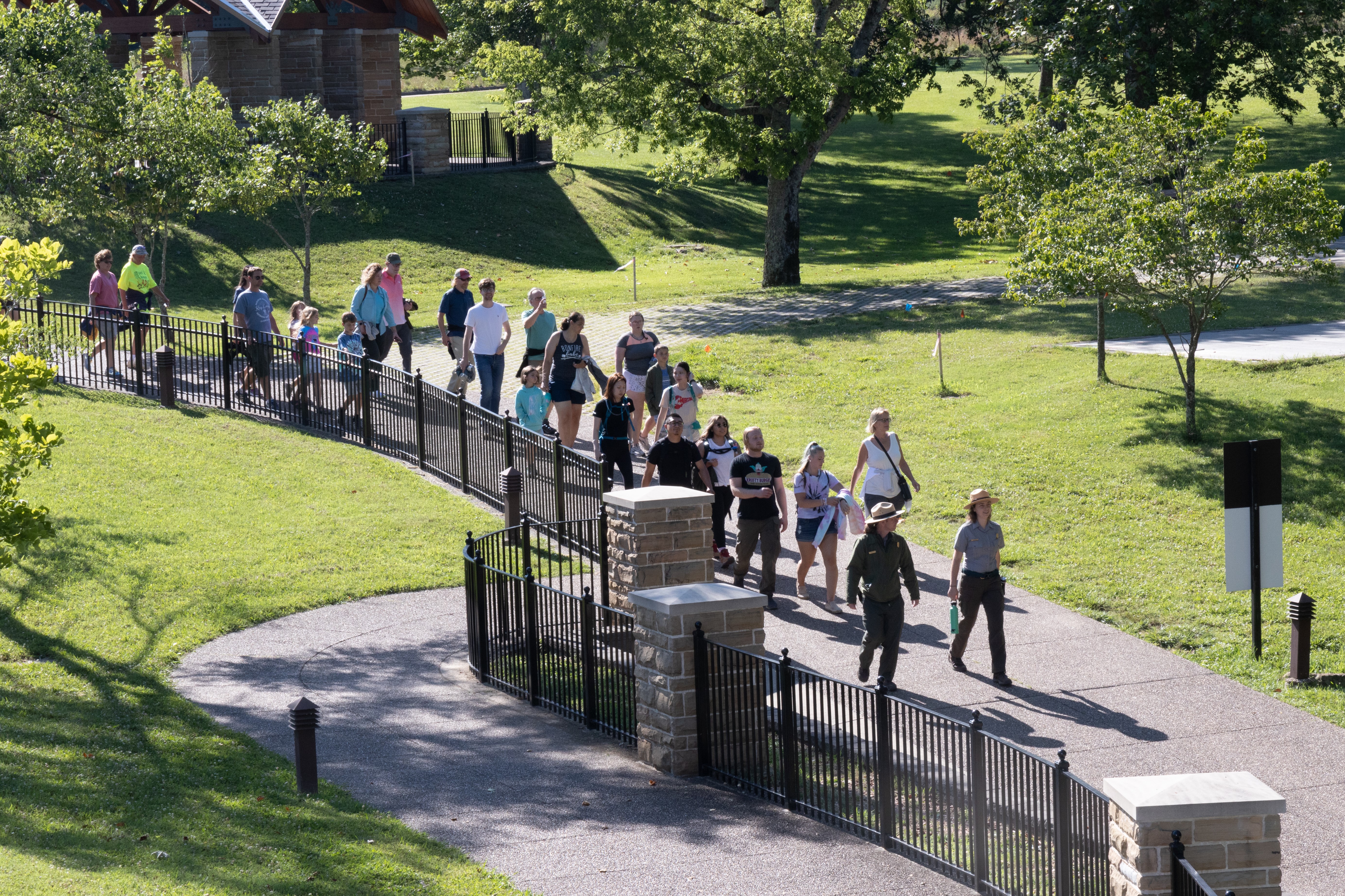 A large group of people walk along a paved pathway.