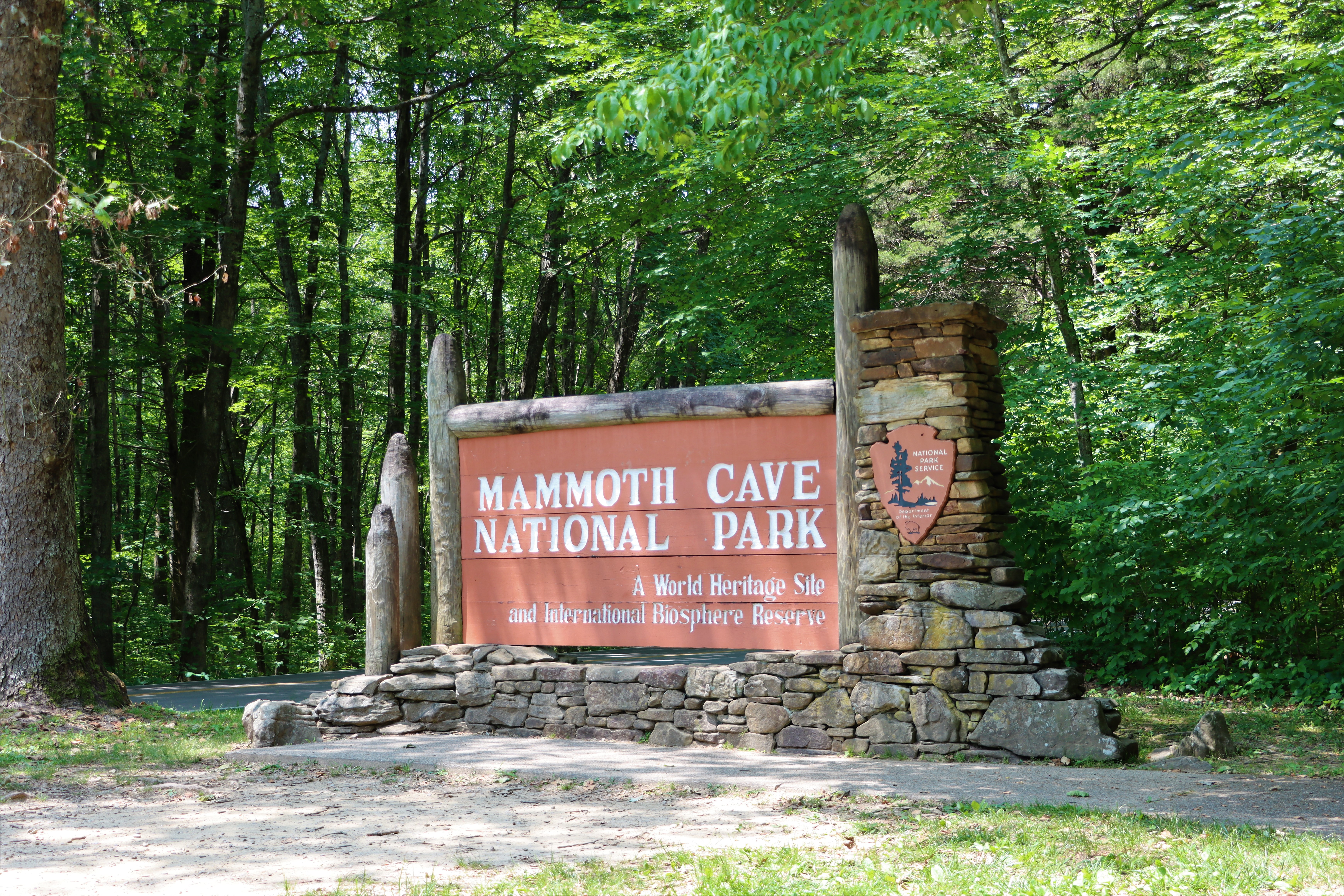 A wooden and stone sign that says "Mammoth Cave National Park, A World Heritage Site and International Biosphere Reserve."