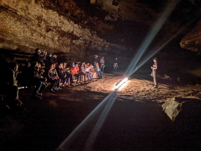 A tour group gathers in the cave on a lantern tour
