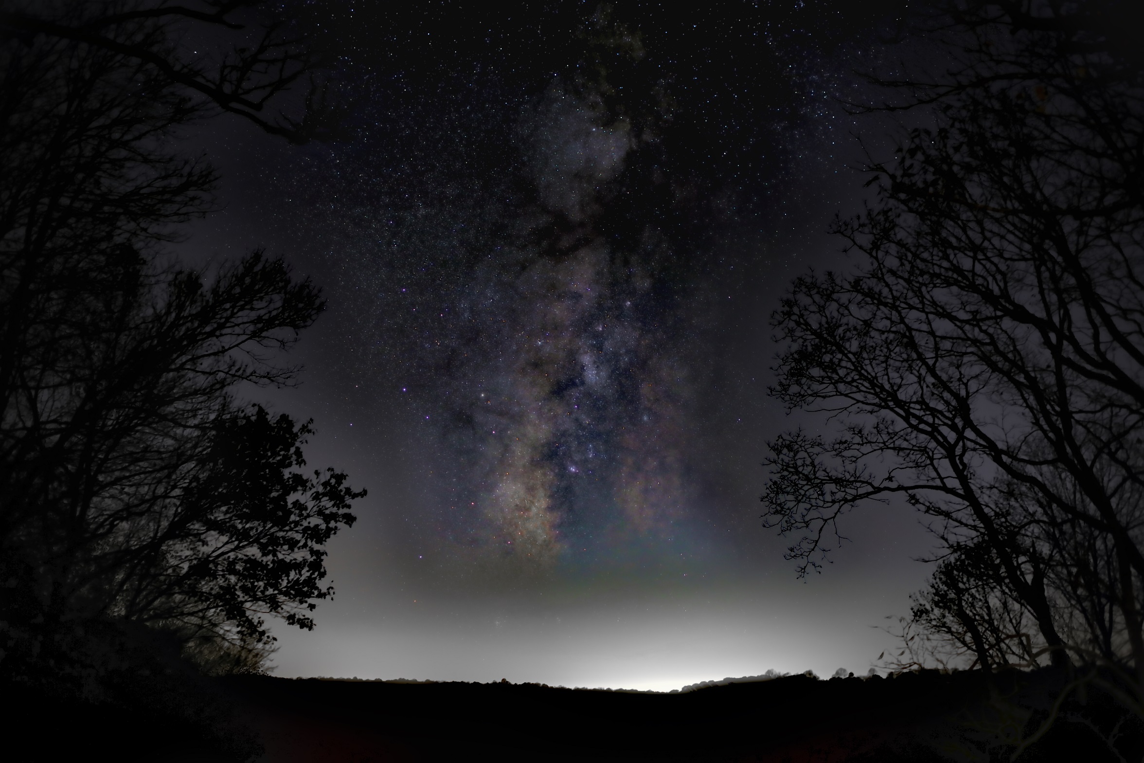 A cloudy haze of stars in a dark night sky is visible above a distant horizon.