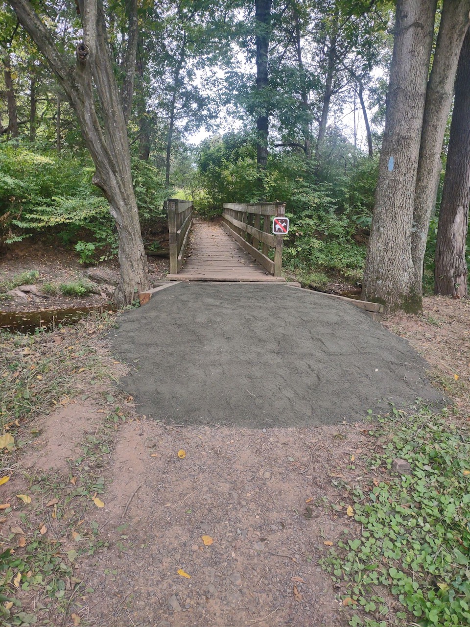 A newly built wooden bridge with trail markings over a creek.