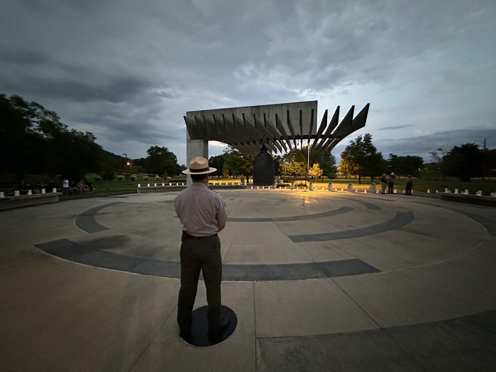 A Park Ranger stands at attention next to the International Friendship Bell.