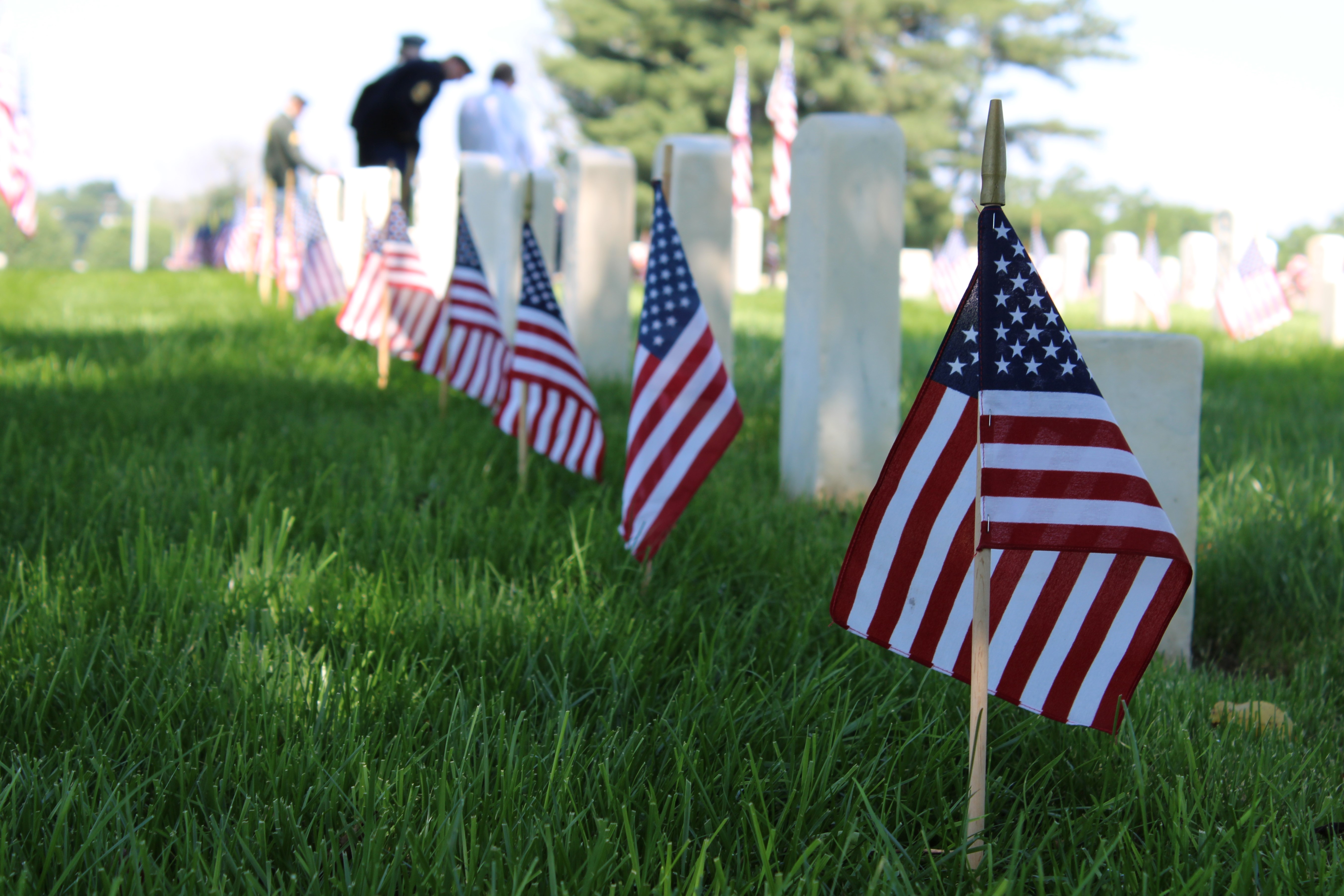 Small American flags stand in front of white graves.