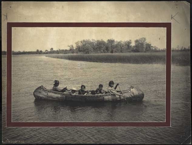 A black and white image of Indian women and children in a canoe.