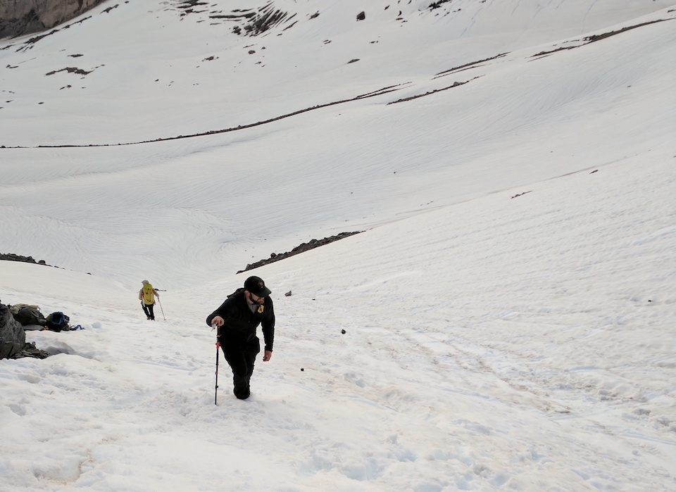 A man hikes up a steep snow covered slope.