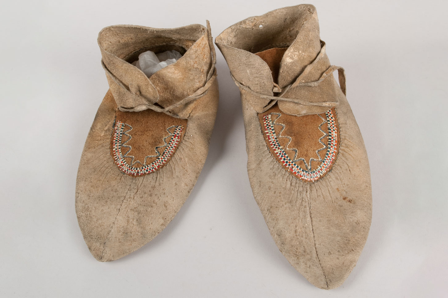 Pair of quillwork moccasins made from two pieces of hide. Quillwork design is a checkered weave of red, blue, and yellow quills.