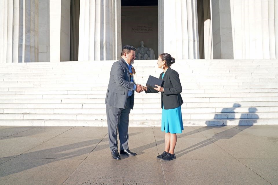 Two people shake hands at the top of the Lincoln Memorial steps