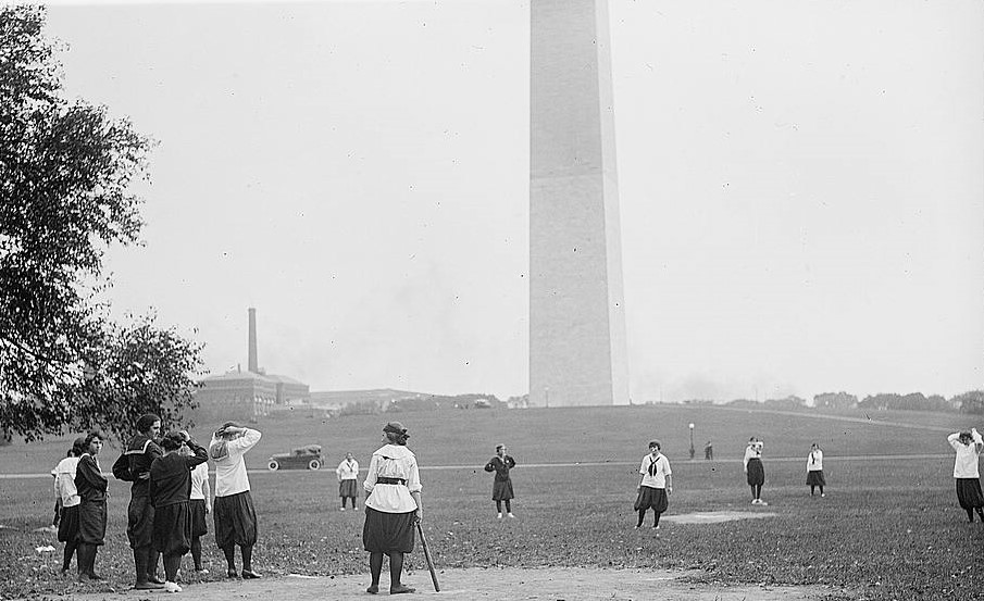 Women playing baseball with the Washington Monument in the background