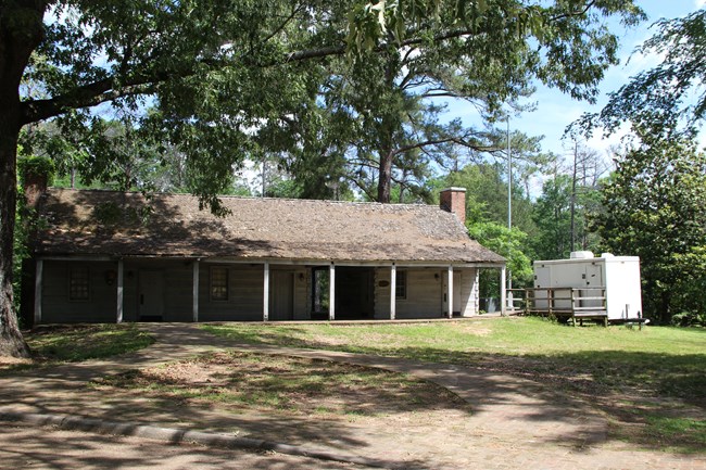 A wooden building with a brick path leading to a breezeway.