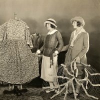 Two women view dress while holding hoop skirt.