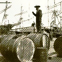 Sepia photo of worker standing on whale oil cask on the dock.