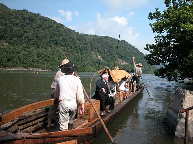 Volunteer assists with batteau boat during park's 25th anniversary celebration