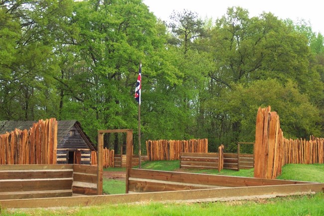 A wooden wall surrounds a building with a British flag flying in the middle.