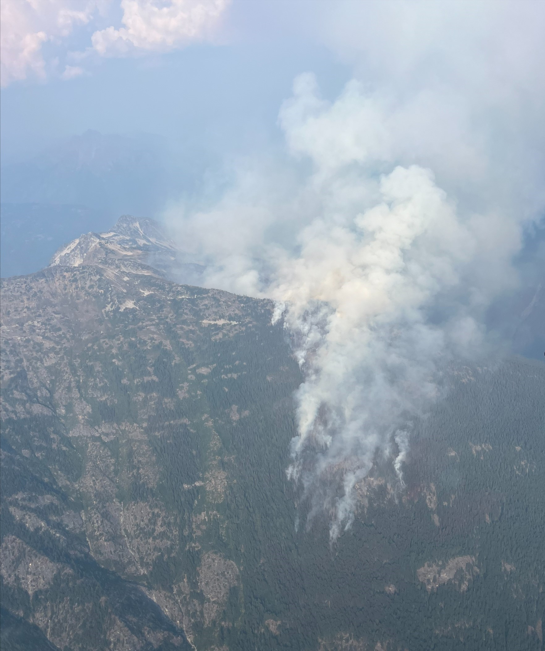 Aerial view of smoke on a tree covered mountainside.