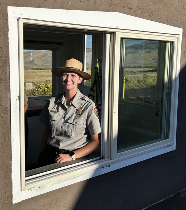 A park ranger greets visitors from inside the entrance station at Great Sand Dunes National Park and Preserve