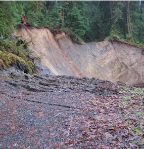 gravel road, ending in a large landslide.  continuation of road can be seen on other side of slide.