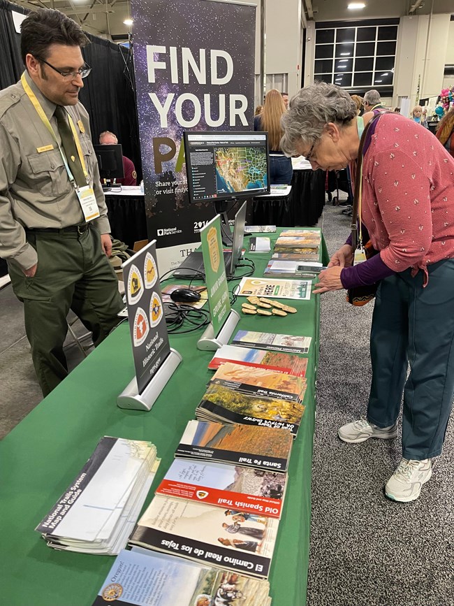 Park ranger stands at a table with literature.