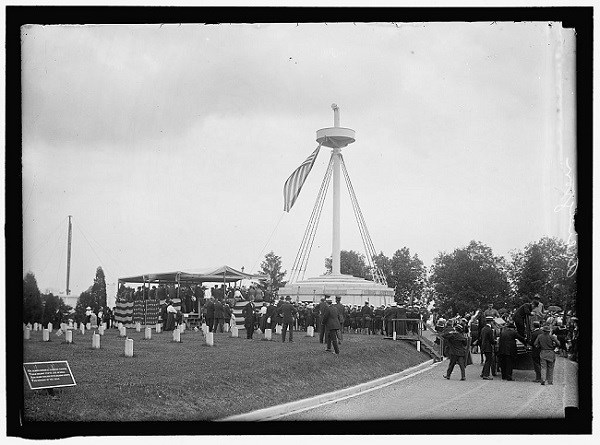 Black and white photo of people surrounding a tall structure