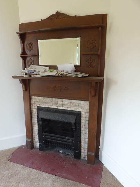 A brown fireplace mantle with a mirror on top