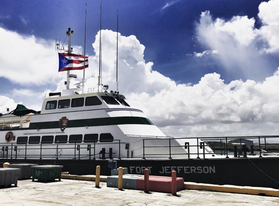 Large vessel with multi-story cabin lined up next to a concrete dockside