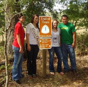 Cherokee youth standing next to pedestrian sign