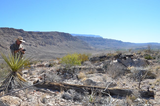 Researcher collecting data on remains of a structure in desert landscape