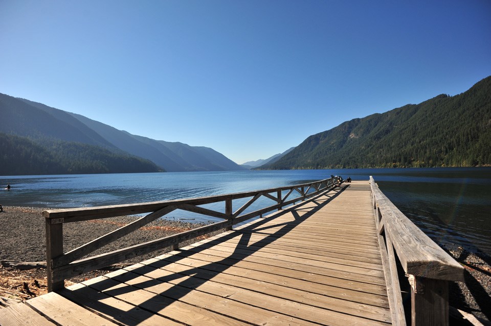 Long wooden dock extends into bright blue water at Lake Crescent Lodge