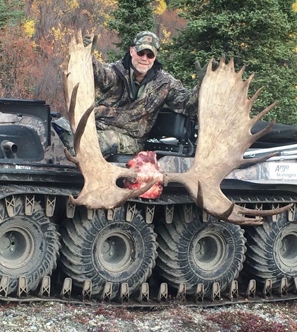 Image of Eric Benson smiling while posing with a moose rack