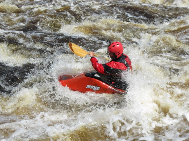 Paddler in a red jackson kayak in whitewater
