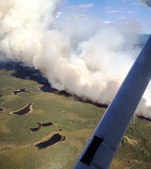 Aerial view of smoke and flames blackening tundra.