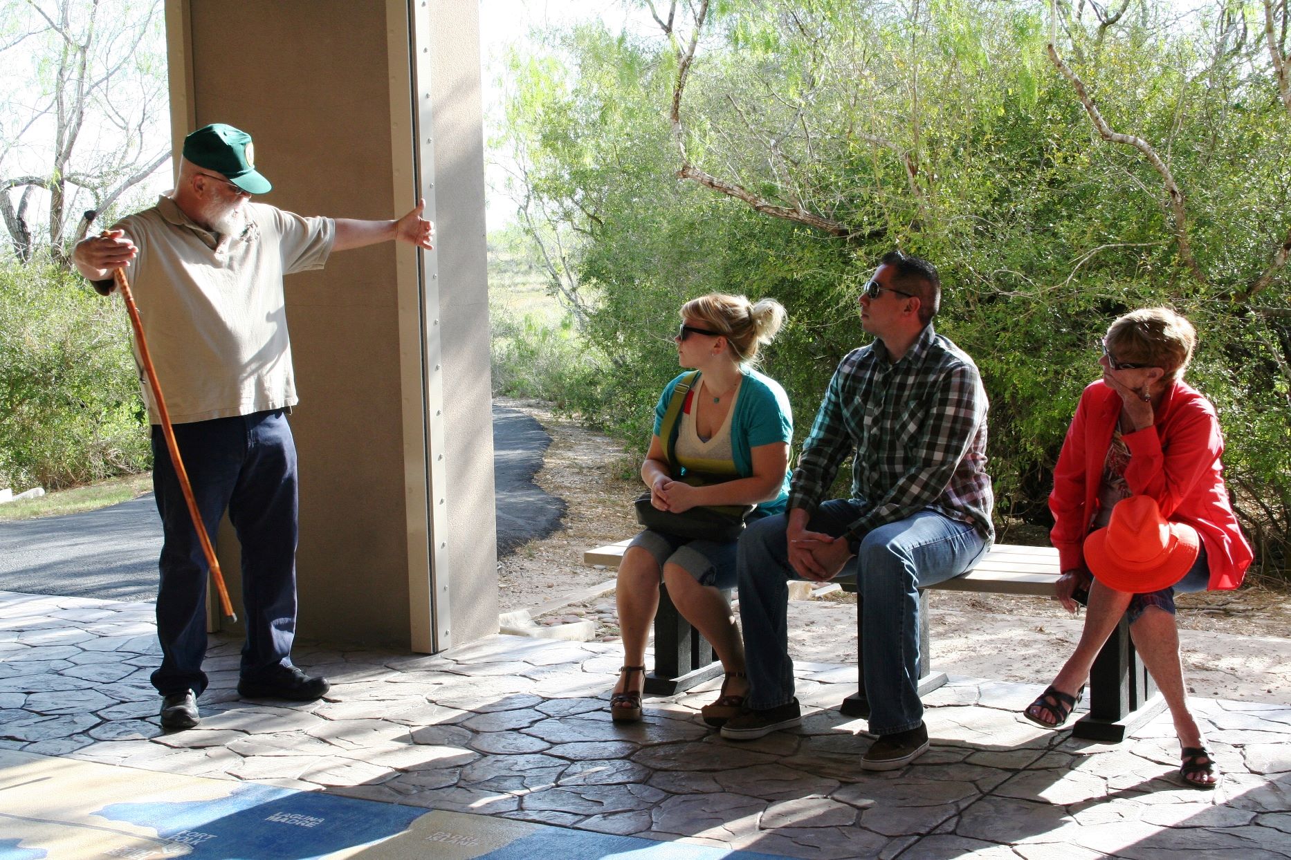 NPS volunteer standing giving a talk to three seated visitors.