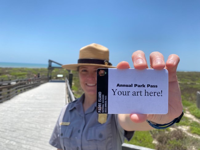 A part ranger holding up a park pass