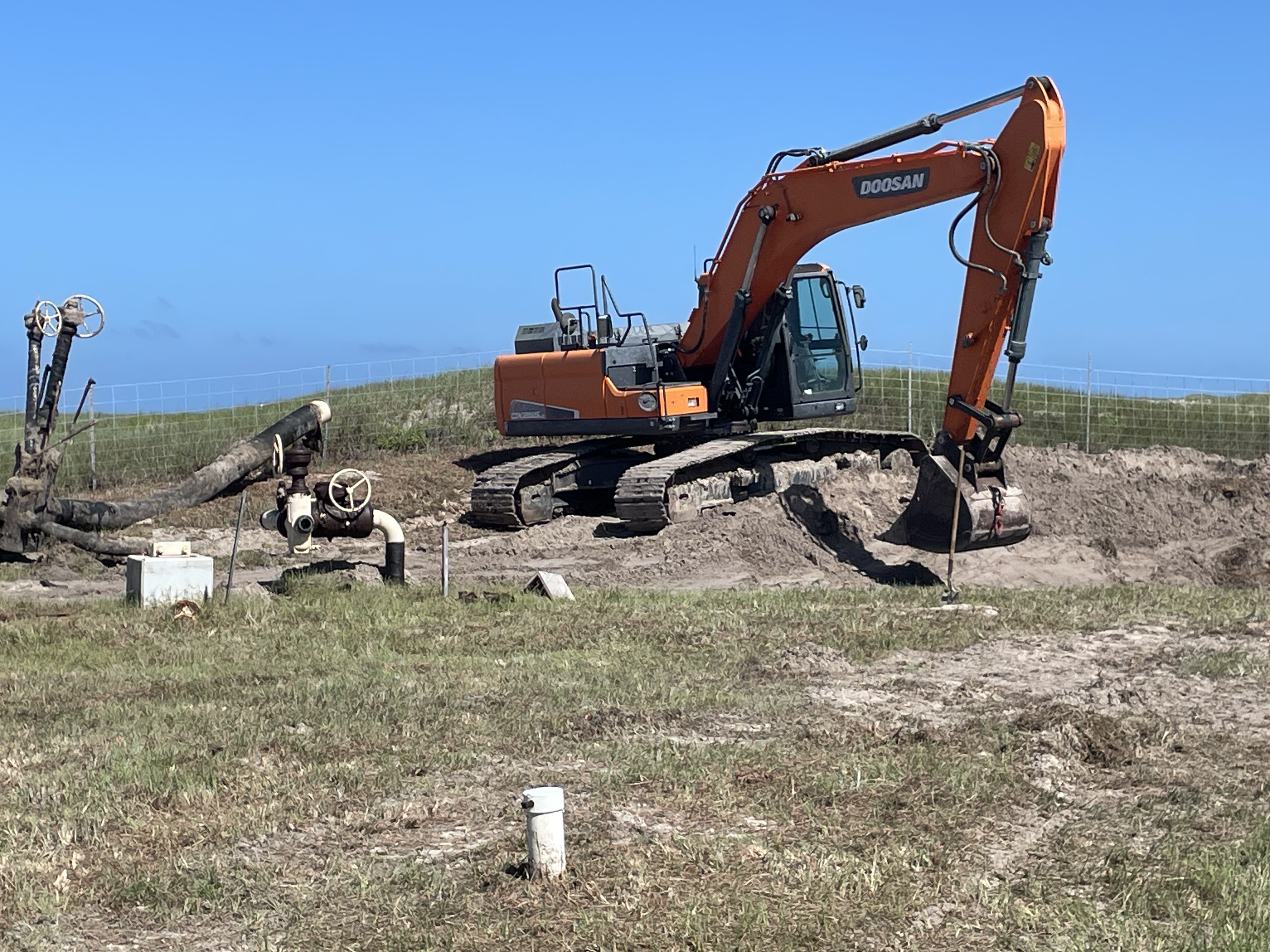 A large orange excavator digs in the ground.