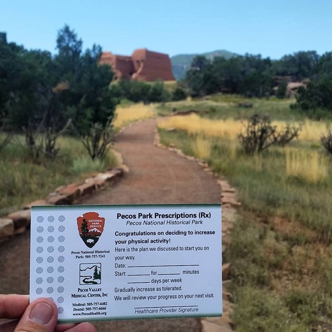 A card being held up with the mission church in the background.